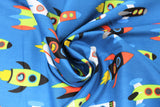 Swirled swatch rocketships fabric (medium dark blue fabric with cartoon rocketships in white, black, red, blue, green, yellow colourschemes all zooming in one direction)