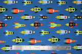 Flat swatch rocketships fabric (medium dark blue fabric with cartoon rocketships in white, black, red, blue, green, yellow colourschemes all zooming in one direction)