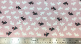 Flat swatch black and white scotty dogs fabric in pink (pale pink fabric with tossed scotty dog silhouettes in white, occasional black with red bandana)