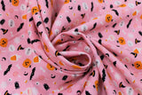 Swirled swatch Spooky Season fabric (pink fabric with tossed halloween related emblems allover: with hats, bats, potions, jack o lanterns, etc.)