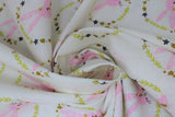 Swirled swatch Bunny Wreath fabric (white fabric with repeated pattern pink drawn style bunnies in circular wreath badges made of yellow, rust and navy greenery/leaves and hearts)