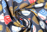 Swirled swatch of baseball print fabric on grey (charcoal grey fabric with tossed white baseballs, brown and tan baseball gloves, red and blue "#1" foam fingers)