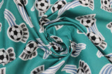 Swirled soccer ball printed fabric swatch in green (medium pale green fabric with black/white soccer balls with sport swoosh lines in blue and "GOAL!" text in black)