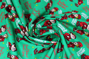 Square swatch jingle jangle fabric (green fabric with white "Jingle Jangle" text, red "The Year Without Santa Claus" text, tossed red and yellow tiny stars, tossed red elf characters allover)