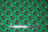 Flat swatch jingle jangle fabric (green fabric with white "Jingle Jangle" text, red "The Year Without Santa Claus" text, tossed red and yellow tiny stars, tossed red elf characters allover)
