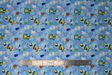Flat swatch movie moments fabric (light blue artic waters/icebergs cartoon look fabric with tossed movie related emblems and text "raised by elves" "bye buddy hope you find your dad" etc., tossed elf logo, polar bears, narwhals, penguins, etc.)