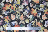 Flat swatch autumn fabric (black fabric with scattered layered leaves in white and orange, blue, green, yellow, purple shades)