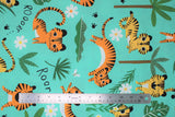 Flat swatch Roar fabric (light turquoise blue/teal fabric with tossed cartoon style baby tigers, tossed green trees and leaves and white floral heads with "Rooarr" text)