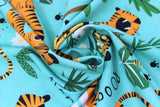 Swirled swatch Roar fabric (light turquoise blue/teal fabric with tossed cartoon style baby tigers, tossed green trees and leaves and white floral heads with "Rooarr" text)