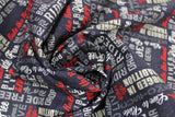 Swirled swatch Biker Life fabric (charcoal grey fabric with white and red biker related text allover in various directions and fonts)