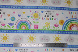 Flat swatch when it rains fabric (white fabric with thick picture space between medium blue stripes with light blue hearts, rainbows, hearts, flowers, suns, clouds within space and "When it rains look for rainbows" "Dream big" text all in fun colours/happy cartoon theme)
