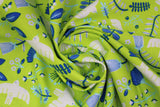 Swirled swatch of Marabella fabric in limelight (lime green fabric with tossed emblems allover in white and teal: doves, assorted floral and greenery)