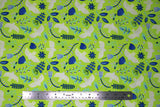 Flat swatch of Marabella fabric in limelight (lime green fabric with tossed emblems allover in white and teal: doves, assorted floral and greenery)