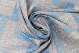Swirled swatch grey collage fabric (grey fabric with collaged horizontal and vertical text allover in white, light blue, and dark blue. Canadian themed words and phrases "Canadian Capers" "Hockey Hero" "Cool" etc.)