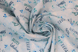 Swirled swatch whale themed fabric in Big Splash Light (splash and whale themed text collage on light blue)