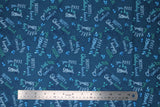 Flat swatch whale themed fabric in Big Splash Dark (splash and whale themed text collage on dark blue)