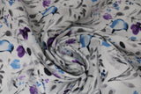 Swirled swatch birdy fabric (white with small tossed floral design in grey, blue, and purple with watercolour effect, tossed large blue birds)