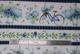 Flat swatch Stripe fabric (white stripes of vases and blue floral and blue old style bikes, thinner white stripes of leaves/greenery and blue floral heads all separated by blue plaid stripes)