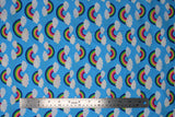 Flat swatch Blue Rainbow fabric (medium blue fabric with rainbow arches with white clouds on both ends allover)