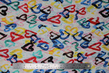 Flat swatch digital printed fabric in hearts (white fabric with tossed finger paint look hearts in red/yellow/blue/green with thin marker drawn looking hearts in pink and green)