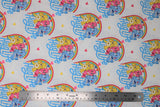 Flat swatch care bear printed fabric in hug life (white fabric with repeated design of yellow, pink, blue care bears walking together with rainbow behind and blue "Hug Life" text in blue, tossed hearts in yellow and pink)