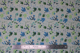 Flat swatch white fabric (white fabric with tossed dinosaur tracks/foot prints allover in various sizes and styles all in green and blue shades)