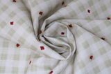 Swirled swatch Canada themed printed fabric in linen (white/beige plaid with red maple leaf accents)