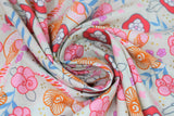 Swirled swatch shell fabric (pale grey beige fabric with brightly coloured tossed floral, greenery, leaves, dots, and birds in cartoon/drawing style in orange, pink, red, blue, purple, gold, grey)