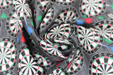 Swirled swatch man cave themed fabric in darts grey (dark grey fabric with tossed dart boards assorted sizes with red/blue/green darts)