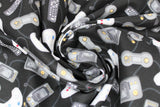Swirled swatch man cave themed fabric in video games black (black fabric with assorted small grey cartoon video game controllers and remotes tossed)