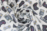 Swirled swatch man cave themed fabric in video games white (white fabric with assorted small grey cartoon video game controllers and remotes tossed)