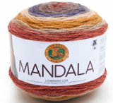 A cake of Lion Brand Mandala yarn in colourway centaur (pale red/orange, beige, mustard, off white, dark purple, taupe)