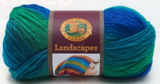 A ball of Lion Brand Landscapes yarn on white background in colourway blue lagoon (blue, teal, green)