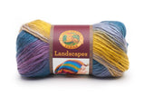 A ball of Lion Brand Landscapes yarn on white background in colourway perfect storm (blue, purple, grey/purple, yellow)