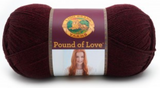 A ball of Lion Brand Pound of Love yarn on white background in shade claret (dark burgundy/purple)