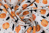 Swirled swatch Crows fabric (pale beige fabric with subtle white spiderweb print background, tossed orange pumpkins with ornate white decoration, tossed black crows and tossed black stars)