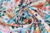 Swirled swatch cool fabric (white fabric with large tossed floral heads, stems and dots in watercolour look in blue, red, purple, orange, yellow colourway)