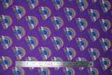 Flat swatch I believe purple fabric (purple fabric with repeated rainbow arches with white clouds on either end and "I believe in" text in blue "unicorns" text in rainbow colours)