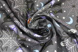 Swirled swatch Grey Creatures fabric (medium grey fabric with ornate look Halloween design allover black vines/leaves and white and grey spider webs with tossed Halloween elements: black cats, orange jack-o-lanterns, white skulls, black bats, orange crescent moons, white stars, purple butterflies)