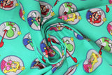 Swirled swatch Super Mario Bros (licensed) print fabric in Super Mario Badges (Mario, Luigi, Peach and Yoshi character badges on light turquoise)