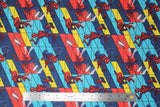 Flat swatch Marvel (licensed) fabric in Spiderman Swing (cartoon swinging spidermans on blue/red/yellow abstract tile with spiders and webs)