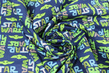Swirled swatch licensed Star Wars (The Child) printed fabric in Child Cut Out Logo (blue/green "Star Wars" text and baby yoda heads on blue)