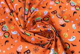 Swirled swatch peekaboo child fabric (orange fabric with tiny tossed halloween elements: black and white ghosts, black bats, black and white spider webs, orange jack-o-lanterns and black "BOO" text with the child coming out of first O)