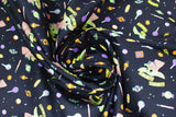 Swirled swatch gimmie candy fabric (black fabric with tiny tossed full colour candies allover with cartoon style the child character in zombie like pose "Gimmie Candy" in yellow text)