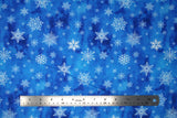Flat swatch of snowflake printed fabric in blue (blue marbled look fabric with white tossed snowflakes in various sizes and styles)