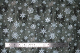 Flat swatch of snowflake printed fabric in grey (grey marbled look fabric with white tossed snowflakes in various sizes and styles)