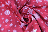 Swirled swatch of snowflake printed fabric in wine (red marbled look fabric with white tossed snowflakes in various sizes and styles)
