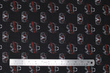 Flat swatch total chaos fabric (black fabric with repeated outline graphics, white car outline with red lights and black flames around, white Cruella outline with red character name text)