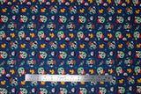 Flat swatch joy to the world fabric (dark blue fabric with lines of holiday related emblems, snowflakes in red, orange, blue, teal colourway, candy canes, snowman heads, tossed Mickey Mouse and Minnie Mouse heads with santa style hats on, gold bells, etc.)