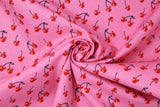 Swirled swatch MM Cherry Sweet fabric (bubblegum pink fabric with tossed black stem cherries with red mickey mouse shaped fruit tossed allover)